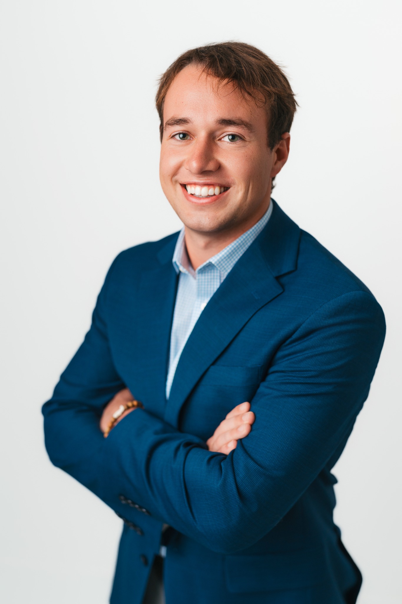 Professional studio headshot of a man in a blue blazer on a white backdrop
